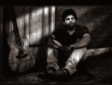 Man sitting alone with his guitar for company