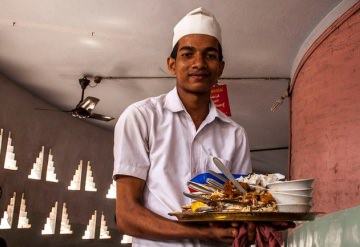 A waiter carrying dirty dishes away