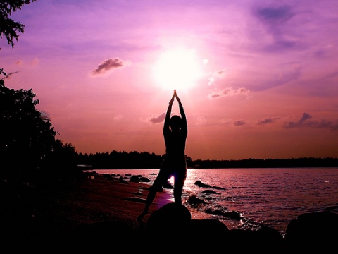 Man performing yoga by the beach